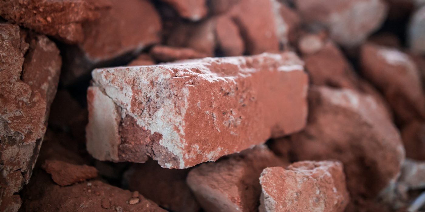 Broken brick and rubbish next to an old ruined building. Dump. Urban economy.