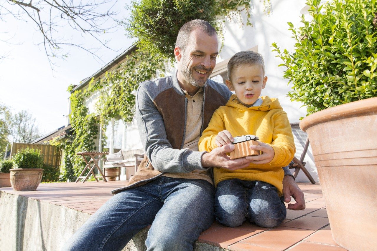 Adult man plays with young boy on patio