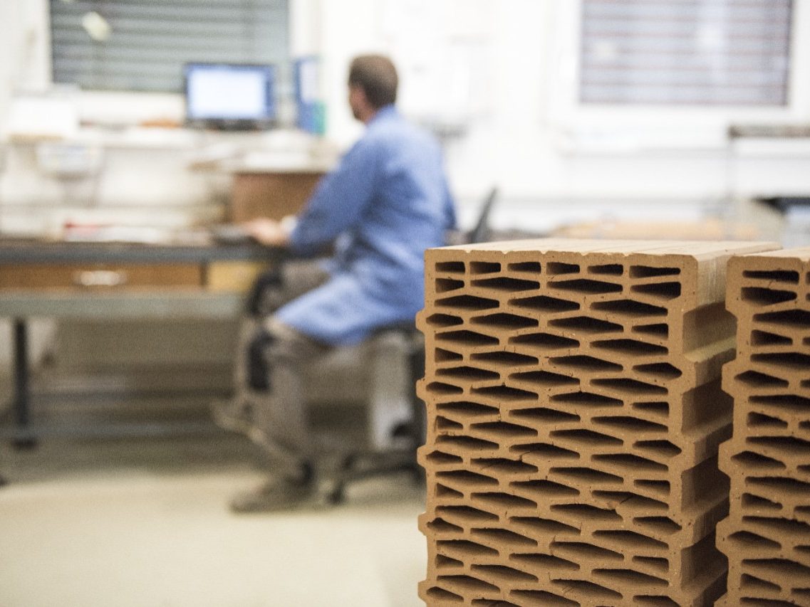 Worker in laboratory with clay blocks in foreground