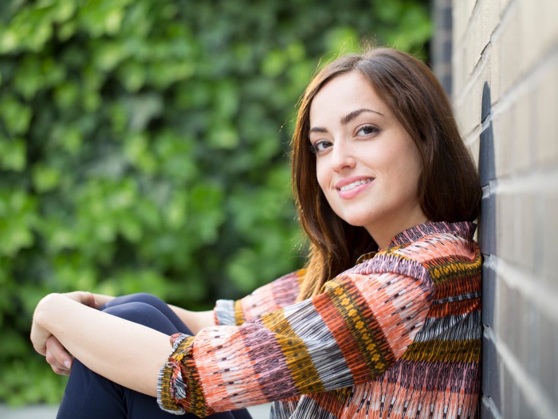 Woman leaning against a Terca Hectic wirecut and braised brick wall