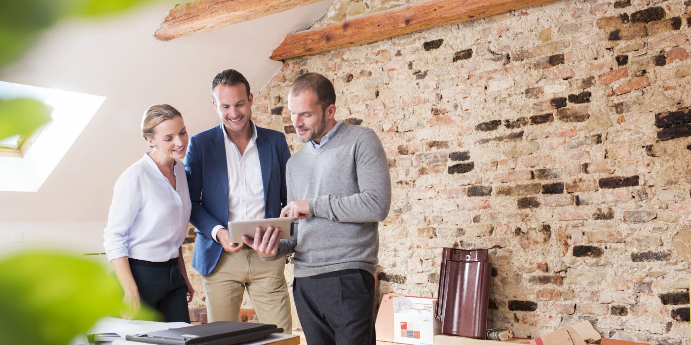 Architect with tablet presenting tablet to end customer at studio in attic loft