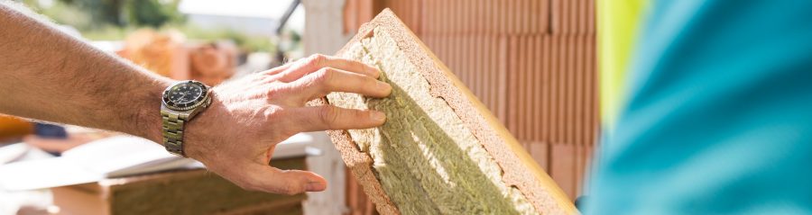 Construction workers touching mineral wool of internal insulation filled clay block