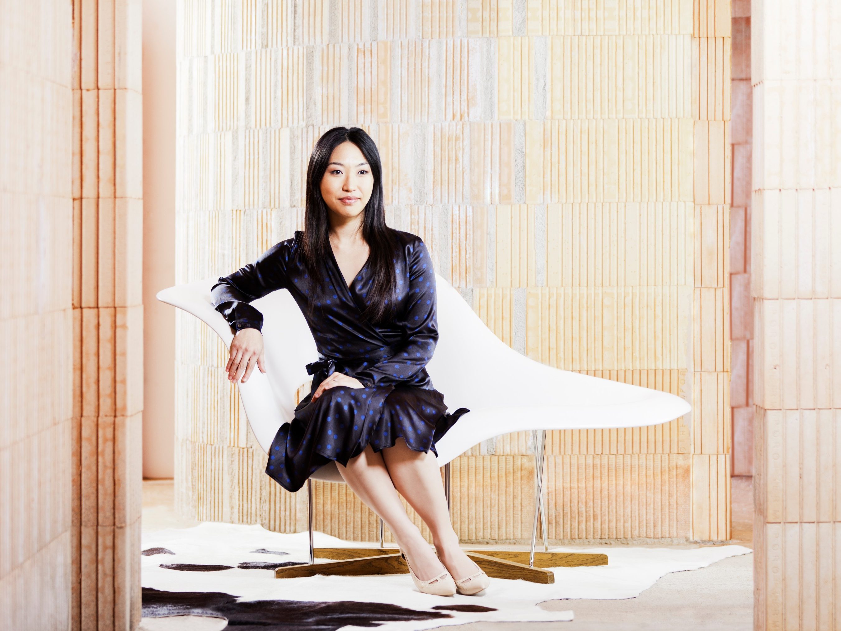 Woman sitting on "La Chaise" Eames chair in unfinished building surrounded by bare brickwork